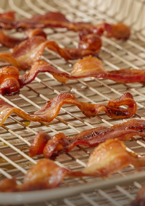 Bacon cooking on a beige Oven Rack