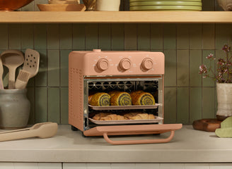 Pink toaster oven with baked goods on a kitchen counter
