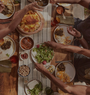 Two people at a table with plates of food, including salad and bread, on a wooden surface.