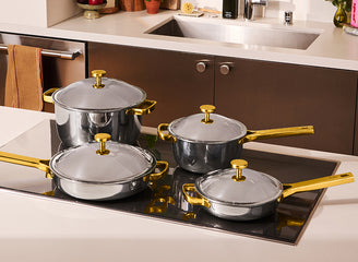 Set of silver pots with gold handles on a kitchen stove