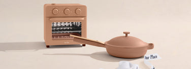 Miniature oven and frying pan set on a beige background