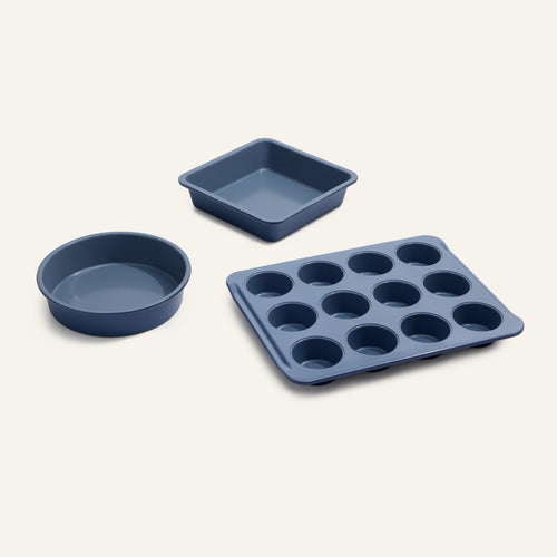 Three blue Wonder Oven Pro Baker’s Kit pans—a round cake pan, a square cake pan, and a twelve-cup muffin tin—arranged on a light background.
