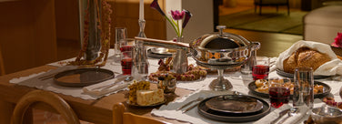 Dining table set with plates, glasses, and a vase with flowers in a restaurant setting.