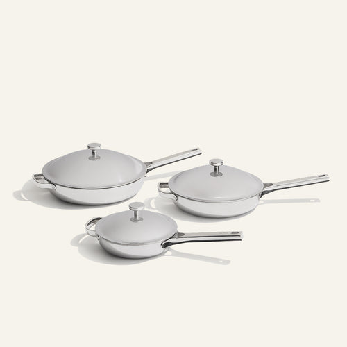 Three stainless steel lidded pans of the Titanium Pro Always Pan Trio (2.0) of varying sizes, arranged on a light surface.