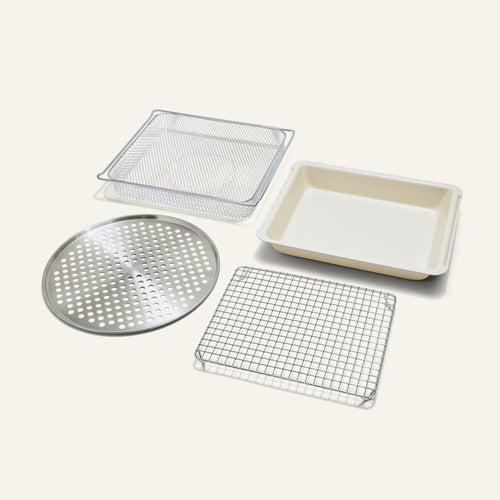 The Wonder Oven Pro Chef’s Kit includes a perforated round tray, square wire rack, mesh basket, and baking pan arranged on a plain light background.